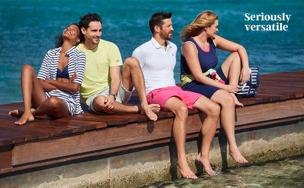 Two couples sitting on a pier off of a body of water.